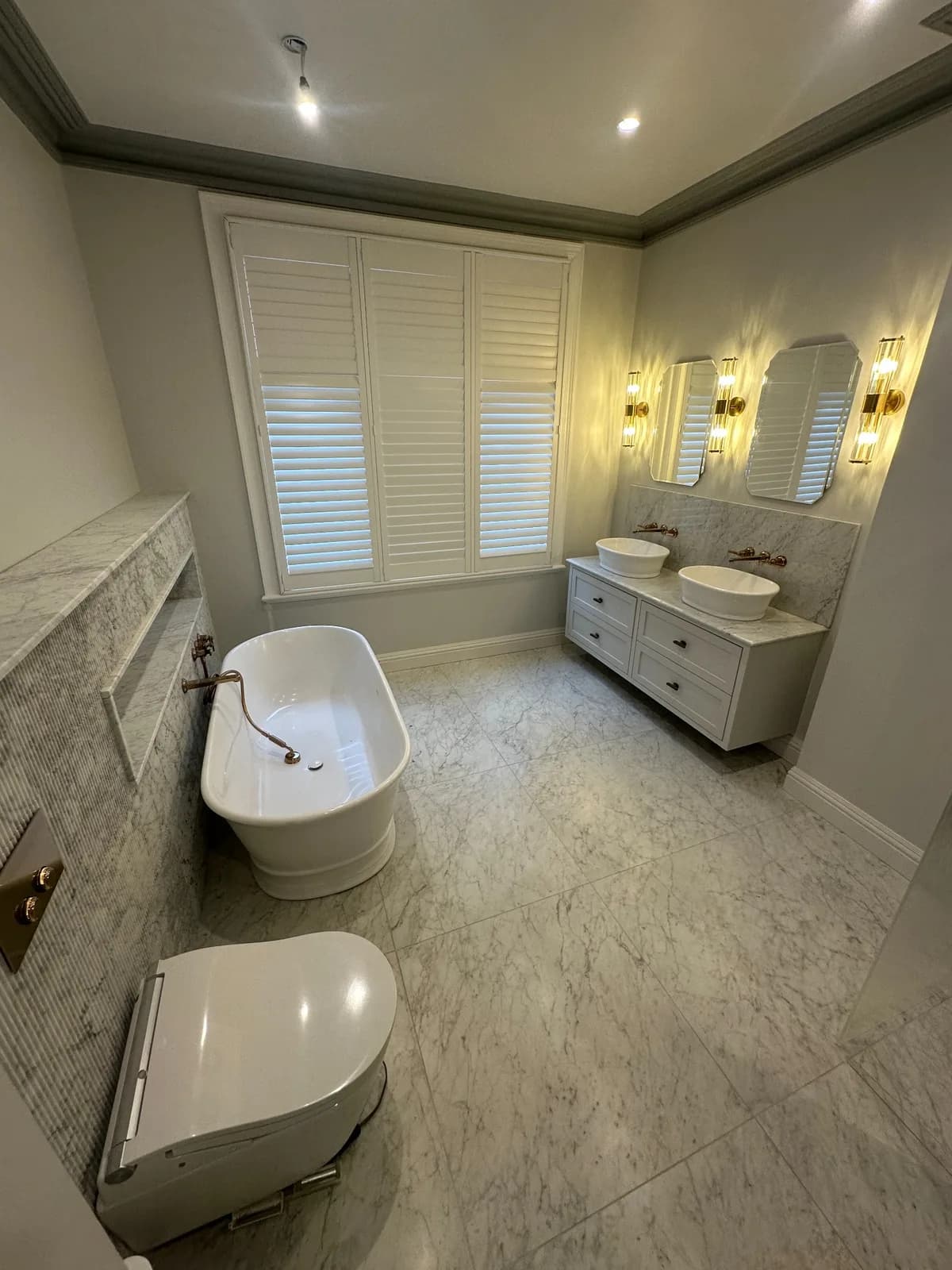 Luxury bathroom with freestanding bath, twin vanity and marble finishes
