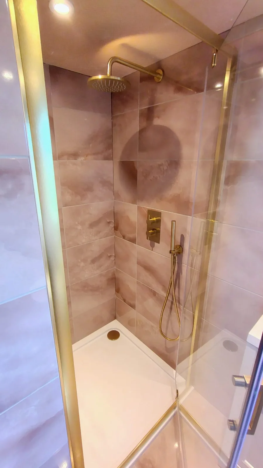 Walk-in shower with concealed controls and coordinated metallic fittings