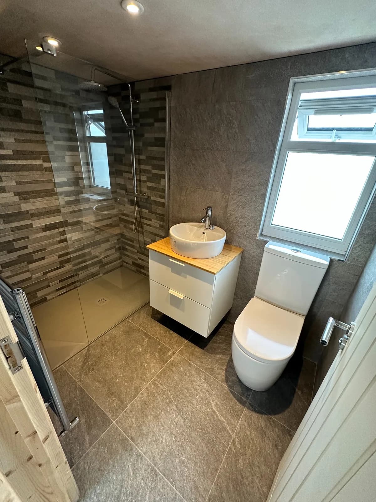 Bathroom with wood-finish vanity, walk-in shower and compact sanitaryware